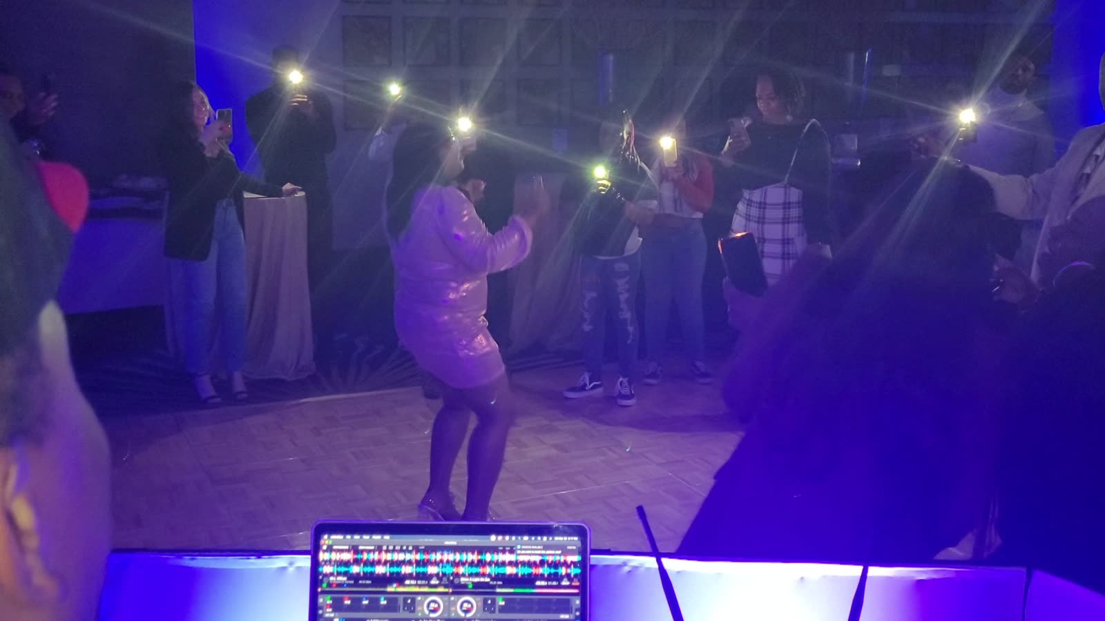 Crowd holding up phone lights around a dancer