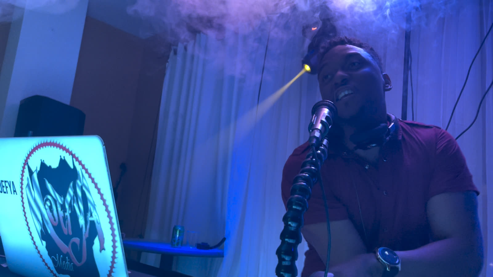 DJ Moefya on the mic under a moving light